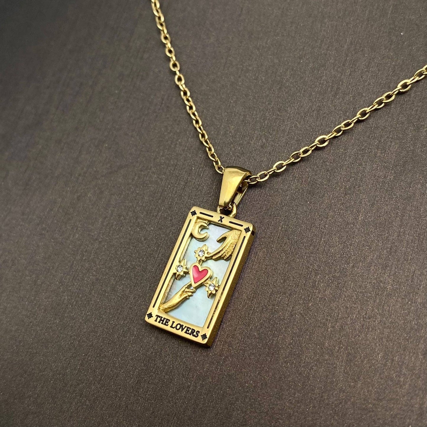 Gold plated pendant with 'The Lovers' tarot card design and chain.

Associated with Gemini, the lovers card deals with duality and unity. Symbolising the notion of the coming together of opposites as an eternal process existing throughout creation. This union is where transformation occurs. 